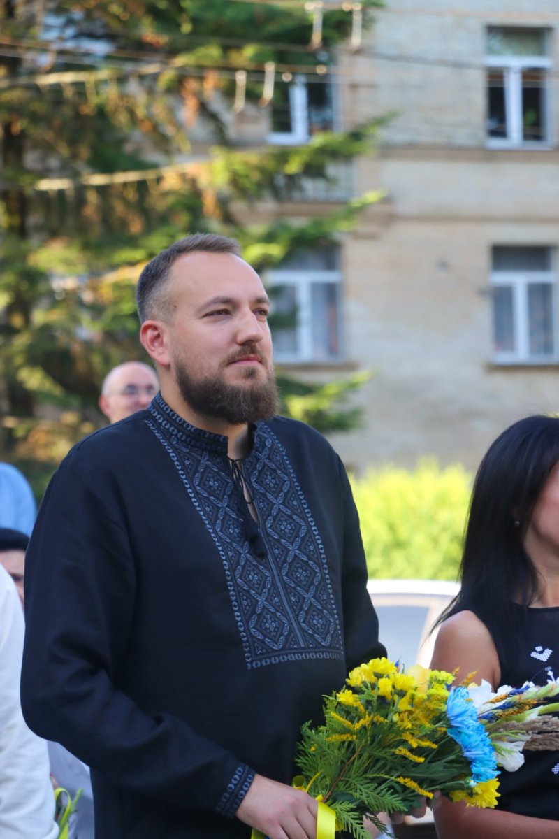 Чоловік у вишитій сорочці тримає квіти.